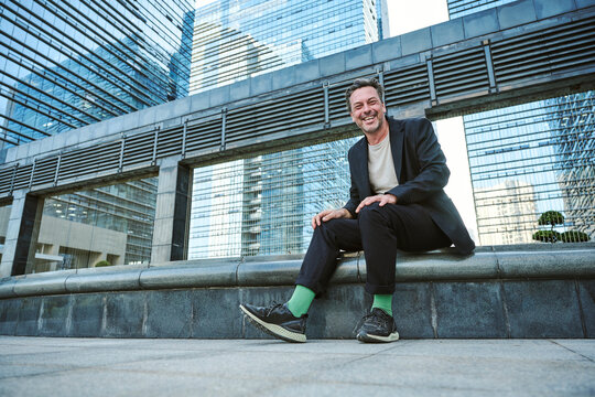 Designer sitting outside of the office's building having rest and smiling