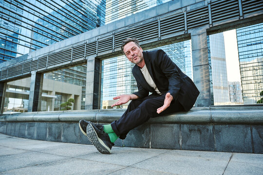 Business man having a call on his smartphone while sitting around office's buildings