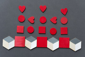 small red hearts discs and squares with some 3d cubes on medium gray paper background