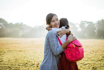 asian mother embrace and hug her daughter wearing uniform when going to school in the morning