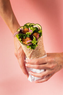 Anonymous person hands holding vegan falafel wrap