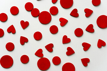 hand painted wooden shapes (hearts) in cadmium deep red acrylic paint on a light background - photographed from above with ambient light