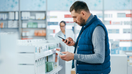 Pharmacy Drugstore: Portrait of Handsome Young Caucasian Man Using Smartphone, Searching to...