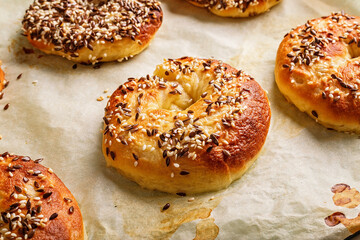 Fresh and crispy New York bagels with sesame seeds. Homemade baking. Hot bagels on baking paper. Cook at home. The best homemade New York-Style Bagel Recipe. Crusty sesame tasty buns. Close-up