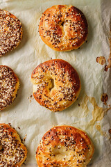 Vertical food banner. Crusty sesame tasty buns. Homemade baking. Fresh and crispy bagels with sesame and flax seeds. The best homemade New York-Style Bagel Recipe. Hot bagels on baking paper. Top view