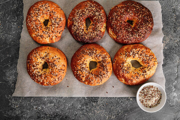 Appetizing and crunchy bagels with sesame and flax seeds. Homemade hot baked goods. Bagels on baking paper on a gray concrete background. Cook at home. Top view. Copy space