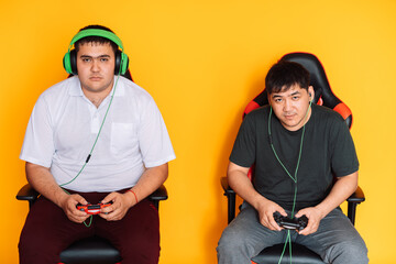Two guys playing video games in front of yellow background