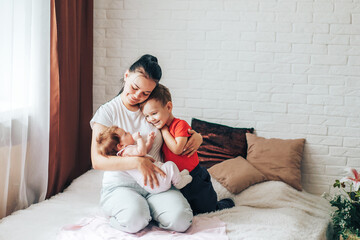 Young mother with two children playing on the bed