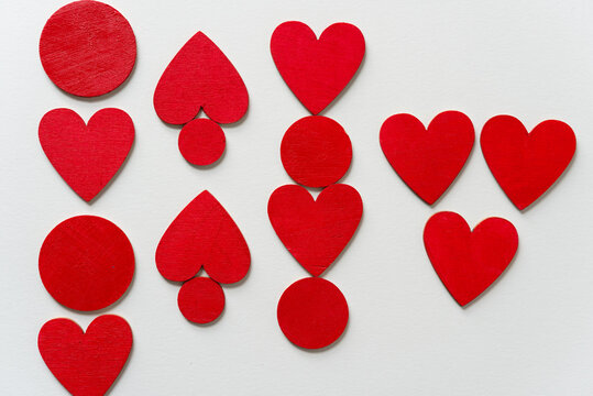 hand painted wooden shapes (hearts) in cadmium deep red acrylic paint on a light background - photographed from above with ambient light
