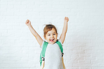 Happy child with raised hands up in front of white background