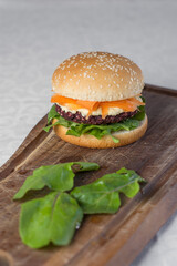 Hamburguesa sobre tabla de madera rustica y con vegetales a su alrededor 