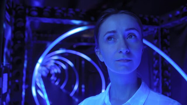 Portrait of woman looking around at interactive museum or exhibition with colorful blue illumination. Futuristic, immersive, entertainment concept