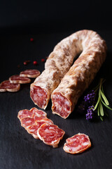 Food concept organic French Salami Saucisson on black slate board with copy space
