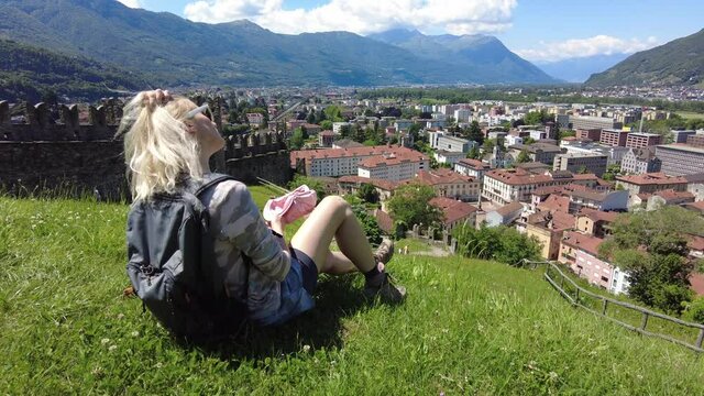 Woman sitting on top of Bellinzona, historic city in Swiss town. Aerial view lookout from Montebello castle. Bellinzona cityscape, capital city of Ticino canton in Switzerland.