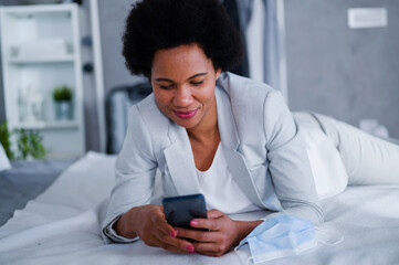 Young black businesswomen just arrived at the hotel taking a rest from a trip, using a smartphone
