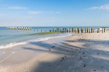 Keuken spatwand met foto Old Naples, Florida pier pilings poles in gulf of Mexico with wooden jetty, many birds, pelicans and cormorants perched or flying by ocean waves © Andriy Blokhin