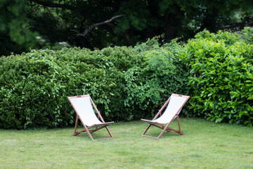 Pair of empty canvas and wood deckchairs on lawn, England, UK