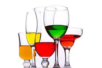 Different types of crystal glasses with colorful liquid inside on white background