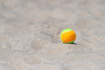 Tennis ball on the sand at the beach close up