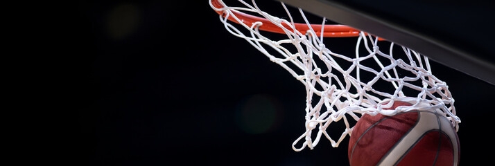The orange basketball ball flies through the basket. Professional sport concept..