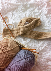 Crochet handwork put beside blurred yarn balls and crochet hook basket