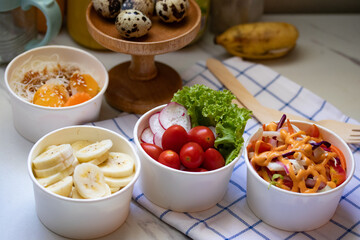Take away healthy food in foil boxes on marble table.