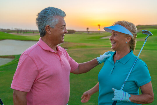 Close-up active senior couple playing golf at sunset