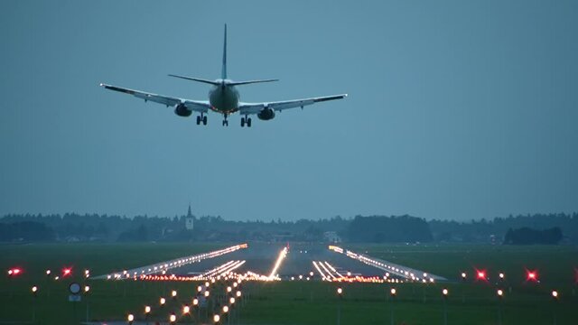 Huge passenger airplane landing on the runway, Ljubljana airport, Slovenia. Aircraft landing. View of long runway spectacularly lit with countless number of colorful lights. Static shot, real time