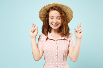 Dreamy pleading smiling happy young redhead curly woman 20s keeps fingers crossed eyes closed...
