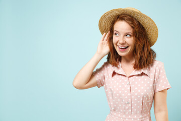 Curious nosy fun smiling young redhead curly woman 20s wear casual pink dress straw hat look aside...