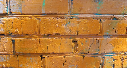   Old brick wall painted with yellow paint with holes, cracks. Rough retro surface. Vintage background for designers, copy space.