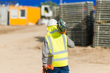 an architect with a laser level walks through the construction area