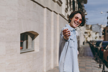 Young fun leader beckoning caucasian woman 20s wearing jeans clothes eyeglasses walk stroll outdoors on city street sidewalk do inviting gesture say follow me. People youth urban lifestyle concept