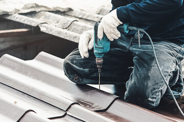 A builder working on the roof. House maintenance. Repair and replacing cement roof tiles.