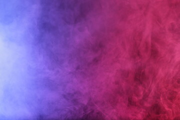 Artifiacial magic smoke in red-blue light on black background