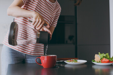 Cropped up photo shot young housewife woman in casual clothes striped t-shirt eat breakfast lunch make teawith boiled water cooking food in light kitchen at home alone Healthy diet lifestyle concept