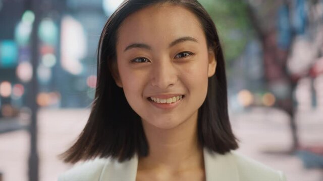 Portrait of Beautiful Japanese Female Wearing Smart Casual Clothes Posing on the Street. Successful Female in Big City Living the Urban Lifestyle. Background with Office Buildings and Billboards.