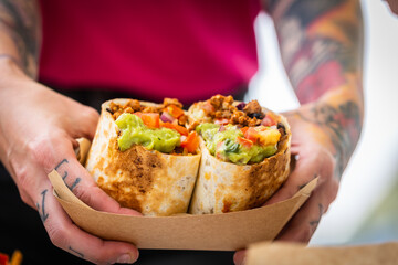 The chef is holding a burrito, close up - obrazy, fototapety, plakaty