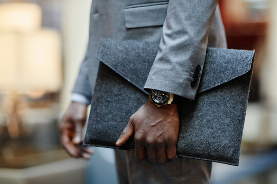 Close up of successful businessman holding document folder while standing in lobby, focus on expensive watch, copy space