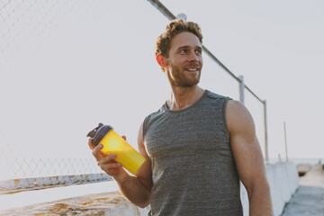 Young sporty strong athletic toned fit sportsman man in sport clothes warm up train drink water...