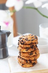 Cookies with chocolate pieces laid on a wooden board with a white napkin