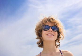 close-up face of a beautiful young woman in sunglasses against the background of the sky. enjoying nature outdoors, relaxation, summer mood, heat. Romance, sunbathing. Copy space © Anna
