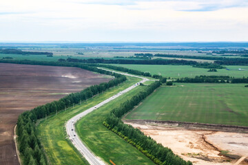 Aerial View Of Highway Road Through Spring Forest Landscape. Top View Of Truck Tractor Unit Prime Mover Traction Unit In Motion On Freeway. Business Transportation, Trucking Industry.