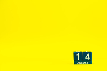 Date 14 August on blue wooden cubes on bright yellow background with place for text
