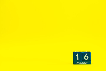 Date of August 16 on blue wooden cubes on a bright yellow background with place for text
