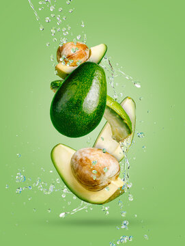 Fresh avocado cut into slices with water drops splash flying in the air and levitate on a mint green background. Healthy diet ingredient recipe. Trendy motion food composition. Creative fruit concept.