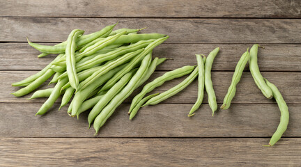 A group of green bean pods over wooden table