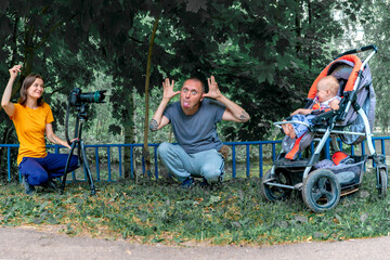 Cheerful crazy family is photographed in the park by the pond
