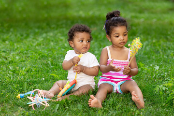 african-American babies a boy with a girl or a brother and sister play on the green grass lawn in...