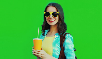 Portrait close up of happy smiling young woman with cup of juice on a green background